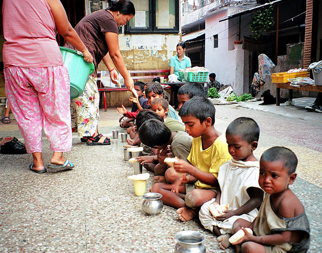 Delhi. Kinder Von Armen Indischen Familien Bekommen Von Tibetern Zu Essen. innen Kinder Bilder Entlang Der Straße
