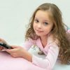 Glückliches Kleines Mädchen Liegt Mit Tablet-Computer Im Bett mit Kinder Bilder Neben Dem Bett