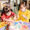 Nette Kinder Mit Down-Syndrom Miteinander Sprechend Und Besprechend über Bilder Kinder Mit Down Syndrom